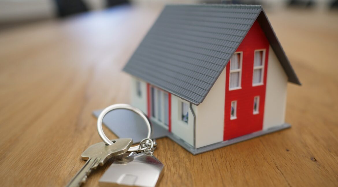 A miniature model of a house next to a set of keys.