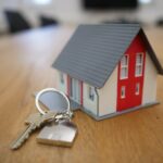 A miniature model of a house next to a set of keys.