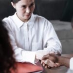 A landlord and her tenant shaking hands in agreement over a property