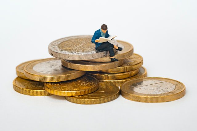 An image of a figurine sitting on a pile of coins.