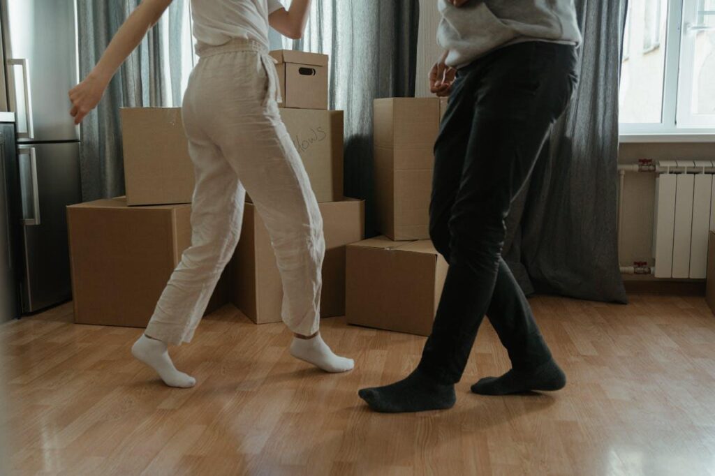 A woman and a man dancing next to a pile of cardboard boxes.